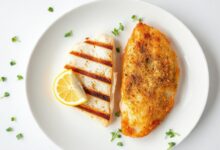 Dois filés de peixe lado a lado em um prato de fundo branco, mostrando a textura macia da merluza e a crocância da empanada da tilápia.