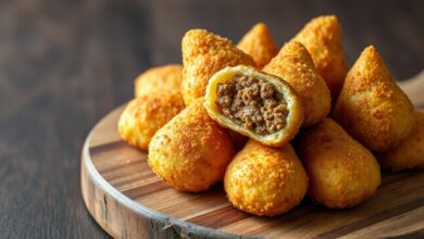 Coxinhas douradas e crocantes, com formato de gota, abertas para revelar o recheio de carne moída.