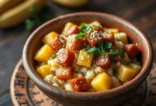 Farofa solta e dourada servida em tigela de barro, com pedaços de calabresa e banana-da-terra à vista.