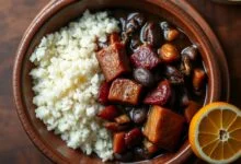 Tigela de barro com feijão preto brilhante, caldo escuro e encorpado, fatias de linguiça calabresa dourada, cubos de bacon crocante e pedaços de costela macia, servida ao lado de arroz branco soltinho e uma fatia de laranja.