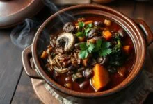 Feijoada de cogumelos servida em tacho de barro, com textura rica e cobertura de coentro fresco.