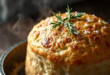 Focaccia dourada, alta, com superfície perfurada, alecrim fresco e cristais de sal grosso, ainda quente com azeite brilhante.