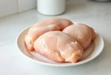 Peitos de frango macios e uniformemente descongelados, prontos para o preparo, em um prato de micro-ondas.