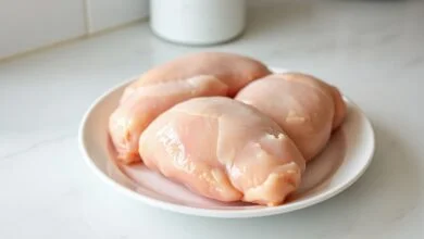 Peitos de frango macios e uniformemente descongelados, prontos para o preparo, em um prato de micro-ondas.