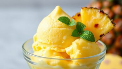 Uma taça de vidro com uma bola generosa de gelado de abacaxi amarelo vibrante e textura aveludada, decorada com um pedaço de abacaxi fresco e folha de hortelã.