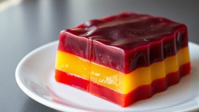 A gelatina finalizada, desenformada em um prato, mostrando camadas perfeitas de morango, limão e uva.