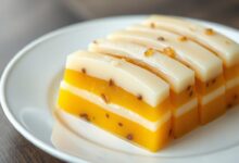 Fatias perfeitas de gelatina com camadas alternadas de creme branco e maracujá vibrante, em um prato de porcelana branca.