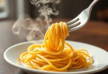 Uma porção de macarrão perfeitamente cozido al dente, com textura firme e cor vibrante, pronto para ser finalizado com um molho.