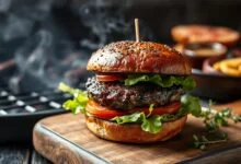 Hambúrguer artesanal com blend de três carnes, com crosta escura e caramelizada, suculento, servido em pão brioche com folhas verdes.