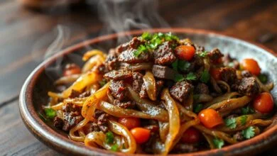 Carne-seca macia desfiada e refogada com cebola dourada, tomates e cheiro-verde, apresentada em um prato rústico.