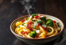 Prato principal de macarrão rigatoni com molho cremoso, raminhos de brócolis vibrantes e pedaços de bacon crocante.