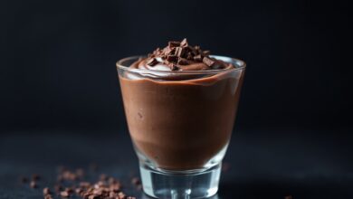 Taça de vidro transparente com mousse de chocolate escura e aveludada, finalizada com raspas de chocolate.