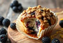 Muffin dourado com topping crocante e amoras suculentas à mostra