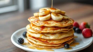 Pilha de panquecas douradas e finas, com textura de crepe, decoradas com fatias de banana caramelizada e um fio de mel.