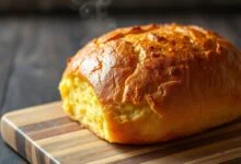 Pão de milho caseiro dourado e macio, com fatias generosas mostrando o miolo fofinho e amarelado.