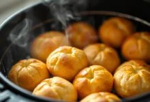 Pães de queijo dourados, inchados e crocantes, prontos para servir.
