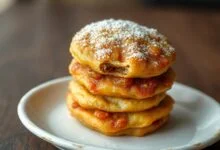 Pastéis dourados e crocantes, cobertos por uma fina camada de açúcar derretido, com o recheio de carne moída levemente visível.