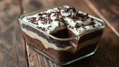 Travessa retangular de pavê de chocolate com camadas perfeitamente definidas de bolo e creme, coberta por uma generosa camada de chantilly e raspas de chocolate, fatiado e pronto para servir.