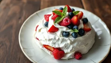 Sobremesa branca e elegante com casca rachada revelando interior macio, coberta por creme chantilly e frutas vermelhas vibrantes.