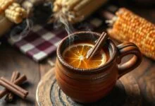 Uma caneca de barro fumegante com a bebida escura e aromática, decorada com especiarias.