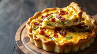 A quiche inteira, dourada e firme, com o recheio cremoso salpicado de bacon e alho-poró, pronta para ser fatiada.