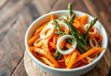 Salada vibrante e fresca em tigela de cerâmica, com fatias finas de cenoura, aspargos e alho-poró, coberta por um molho cremoso e alaranjado de damasco.