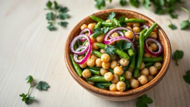 Tigela com salada vibrante de vagens verdes crocantes, grão de bico dourado, cubos de tomate e fatias de cebola roxa, finalizada com folhas de hortelã fresca.