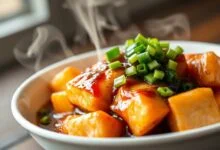 Cubos de salmão dourados cobertos por molho aveludado e cebolinha fresca.