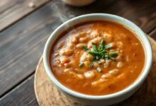Tigela de sopa de feijão cremosa e aveludada, servida com um fio de azeite e cebolinha.