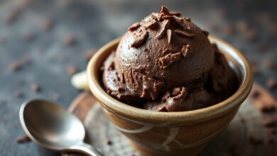 Porção generosa de sorvete de chocolate escuro e aveludado, servido em tigela de cerâmica rústica, com lascas de chocolate e uma colher.