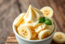 Tigela de sorvete de banana caseiro com textura aveludada, servido com fatias de banana fresca e folhas de hortelã.