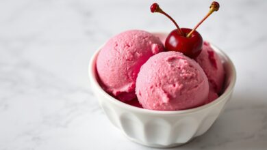 Tigela elegante de sorvete rosa-vibrante, com textura sedosa e guarnição de cerejas frescas, perfeita para um verão sofisticado.