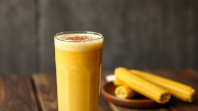 Bebida dourada e espessa servida em copo de vidro, com um toque de canela.