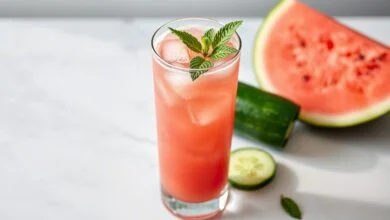 Bebida vibrante rosa-claro, fresca e espumosa, servida em copo alto com gelo e hortelã.