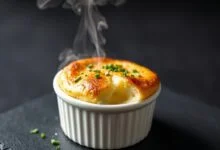 Suflê dourado e inflado, saindo do forno com interior cremoso e cheiro-verde fresco.