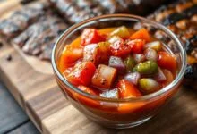 Tigela de vidro com vinagrete fresco de tomate, cebola roxa e pimentão em cubos uniformes, brilhante de azeite, pronto para acompanhar a carne assada.