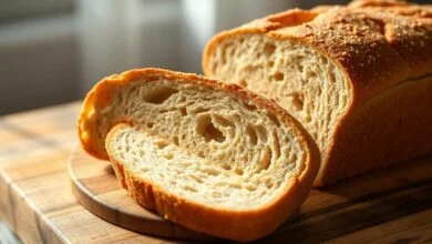 Pão integral alto e dourado, fatiado sobre uma tábua rústica com miolo macio visível.