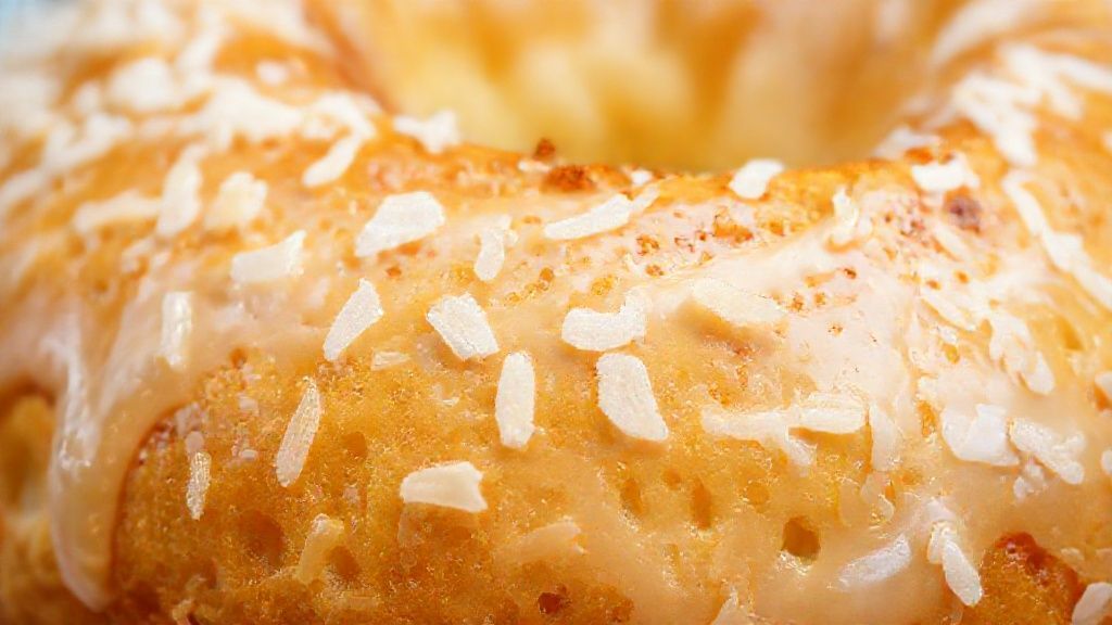 Close-up da rosca doce dourada com cobertura brilhante e textura fofa.