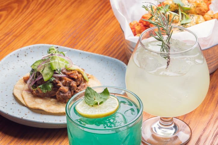 Gin tônica em uma taça, decorado com fatias de limão, ramo de alecrim e grãos de zimbro.
